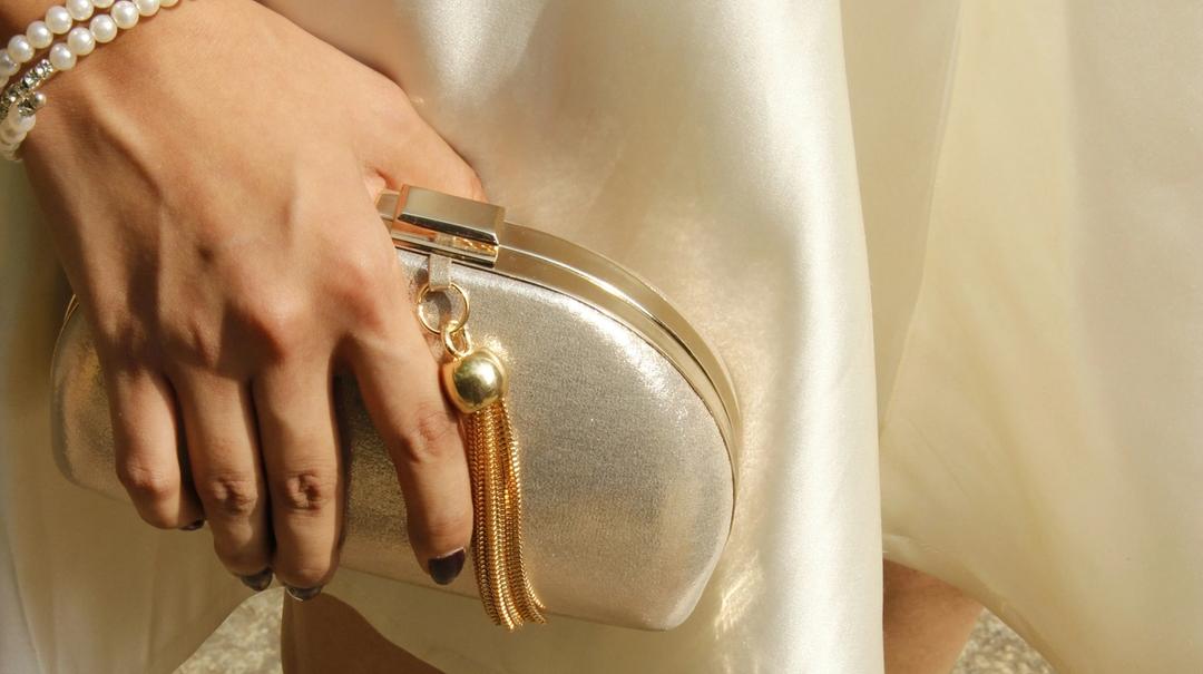 A close up of a woman wearing white holding a clutch.