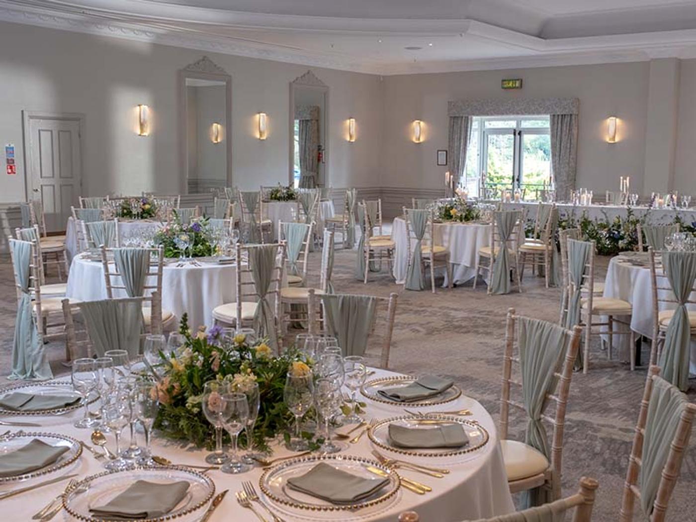 St. Pierre Suite laid out for a wedding breakfast with round tables and sage green chair sashes
