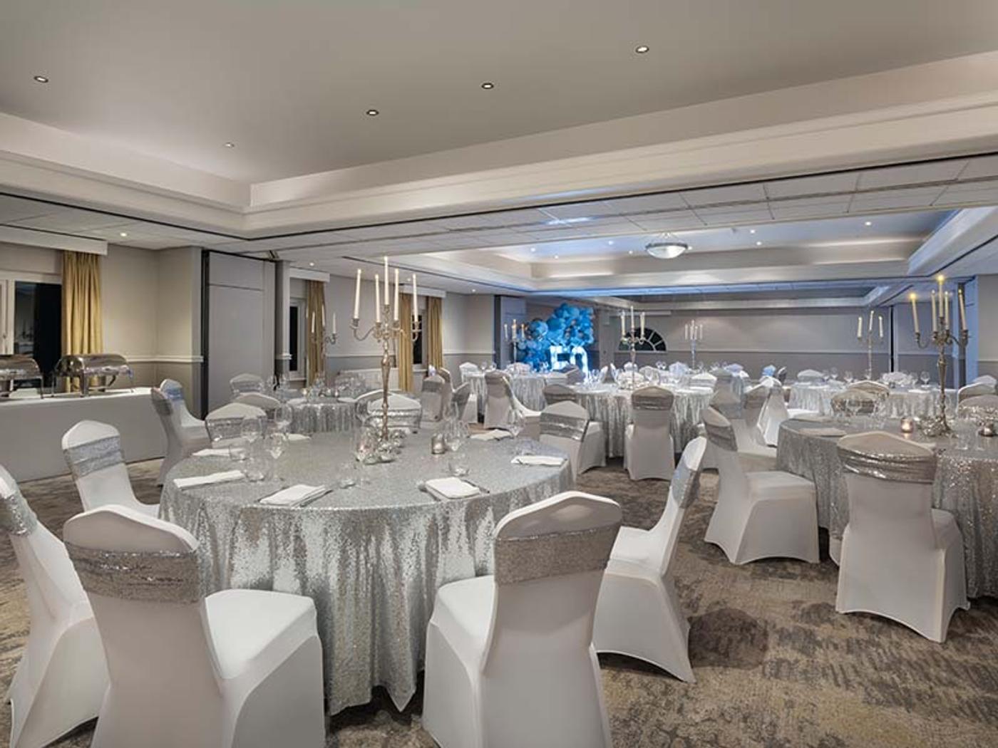 Silver-themed celebration room set with round tables and a light-up '50' display