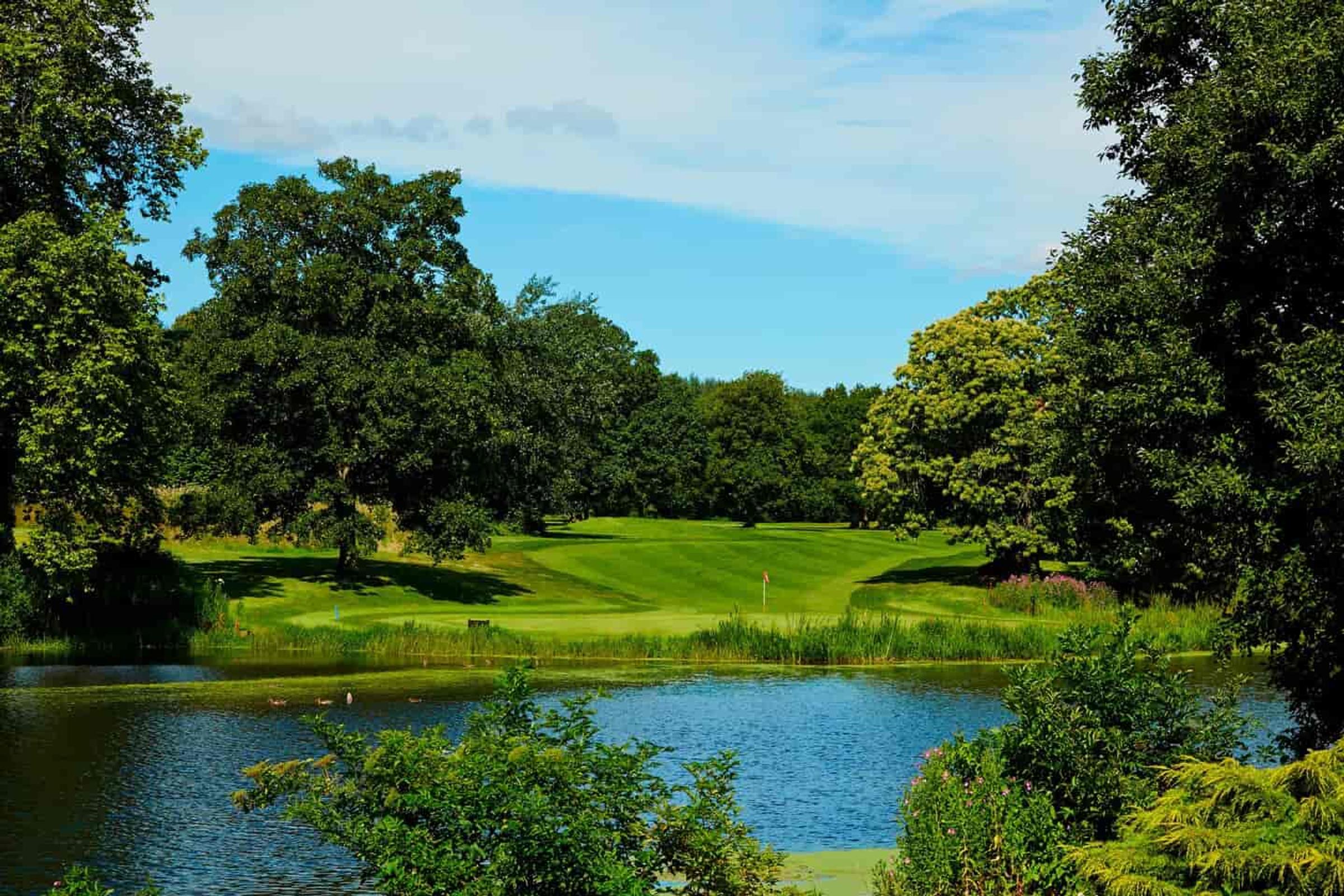 Delta Hotels St. Pierre Country Club golf green beside the lake, framed by trees