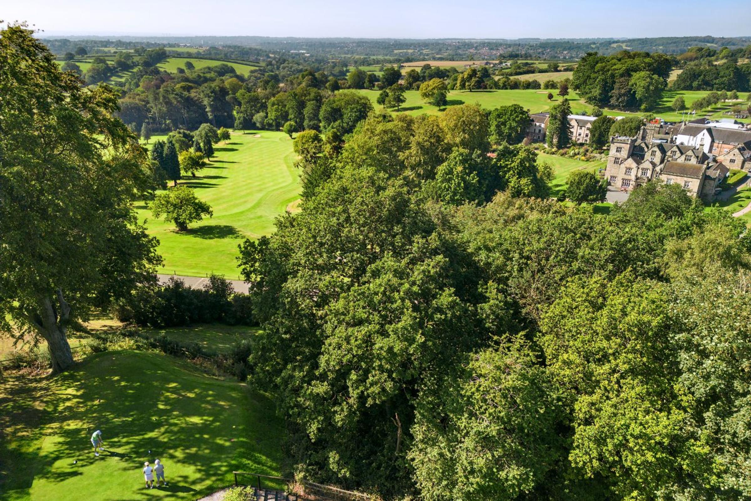 Aerial view over trees of Delta Hotels Breadsall Priory Country Club's golf course and clubhouse
