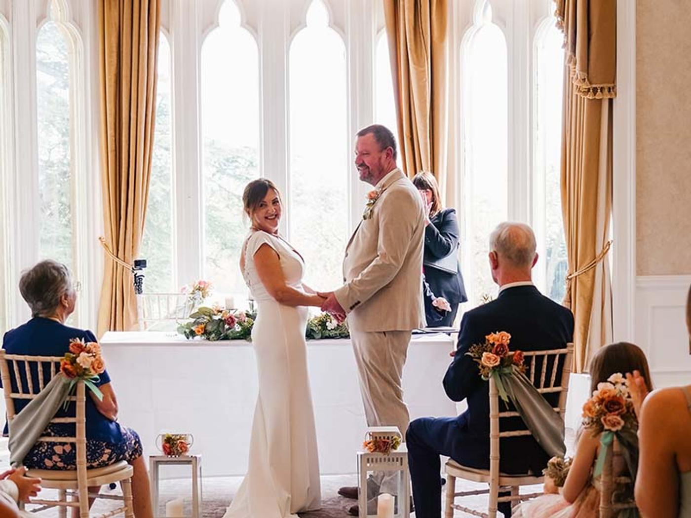 Bride and groom holding hands during their ceremony at Delta Hotels Breadsall Priory Country Club