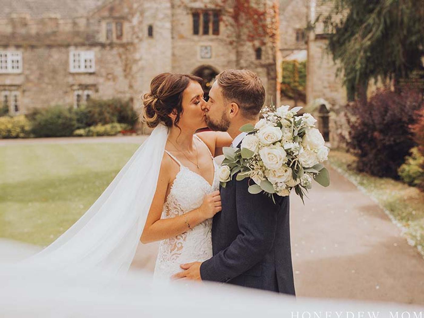 Couple embracing beneath Delta Hotels St. Pierre Country Club's archway with the lawn beyond