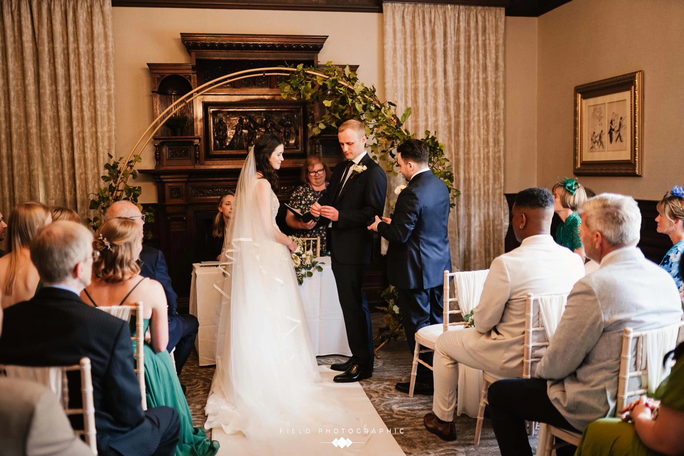 Bride and groom exchanging vows beneath a floral arch at Delta Hotels Breadsall Priory Country Club