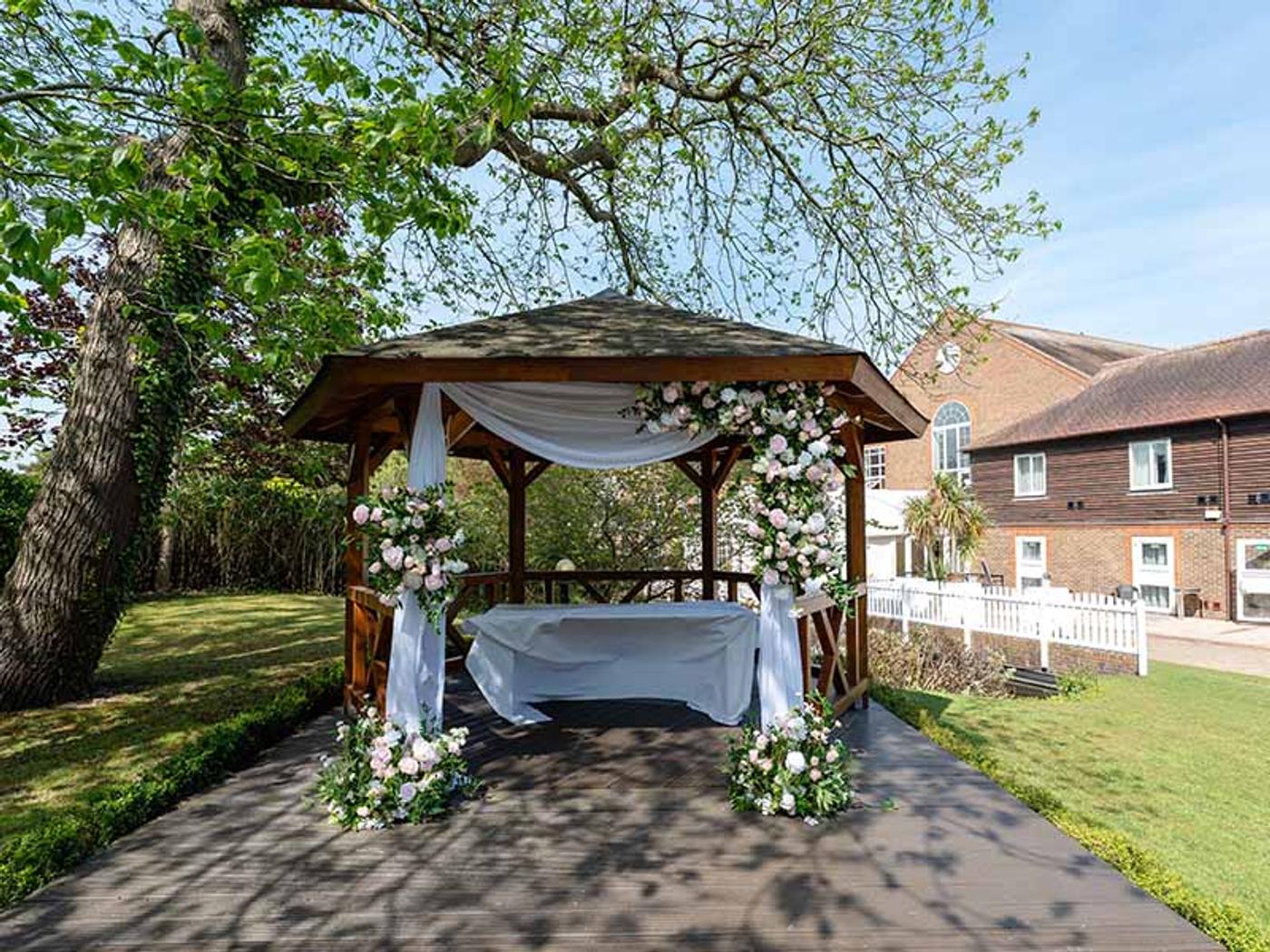Rows of white ceremony chairs facing the flower-covered gazebo at Delta Hotels by Marriott Tudor Park Country Club
