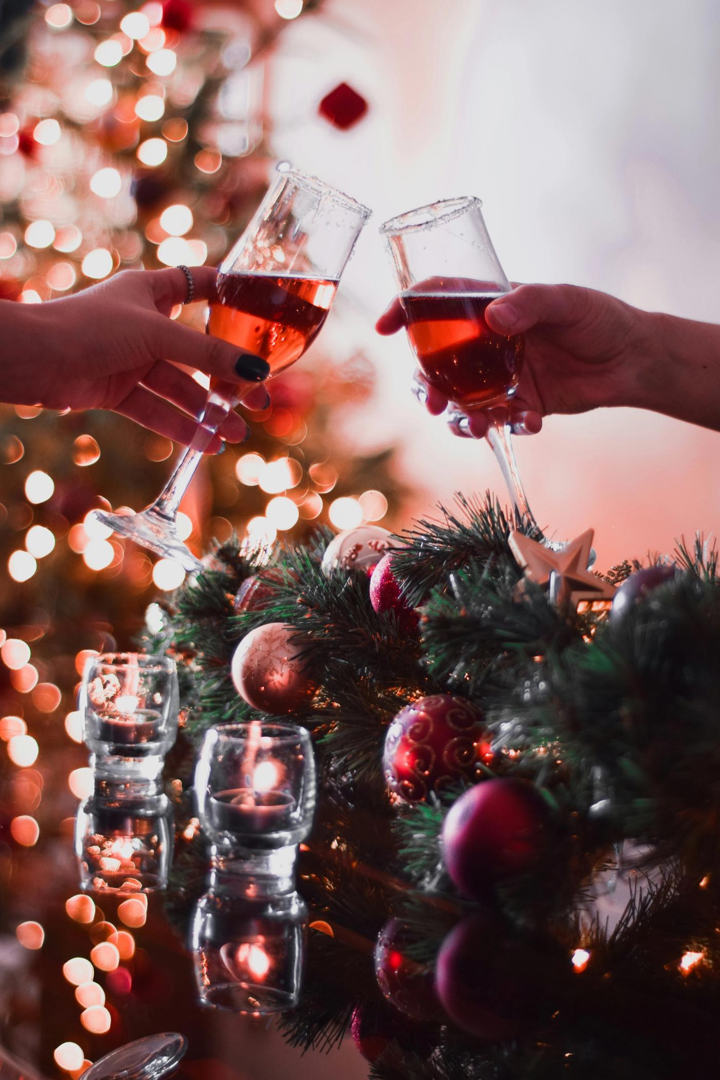 Two people saying cheers in front of Christmas decorations