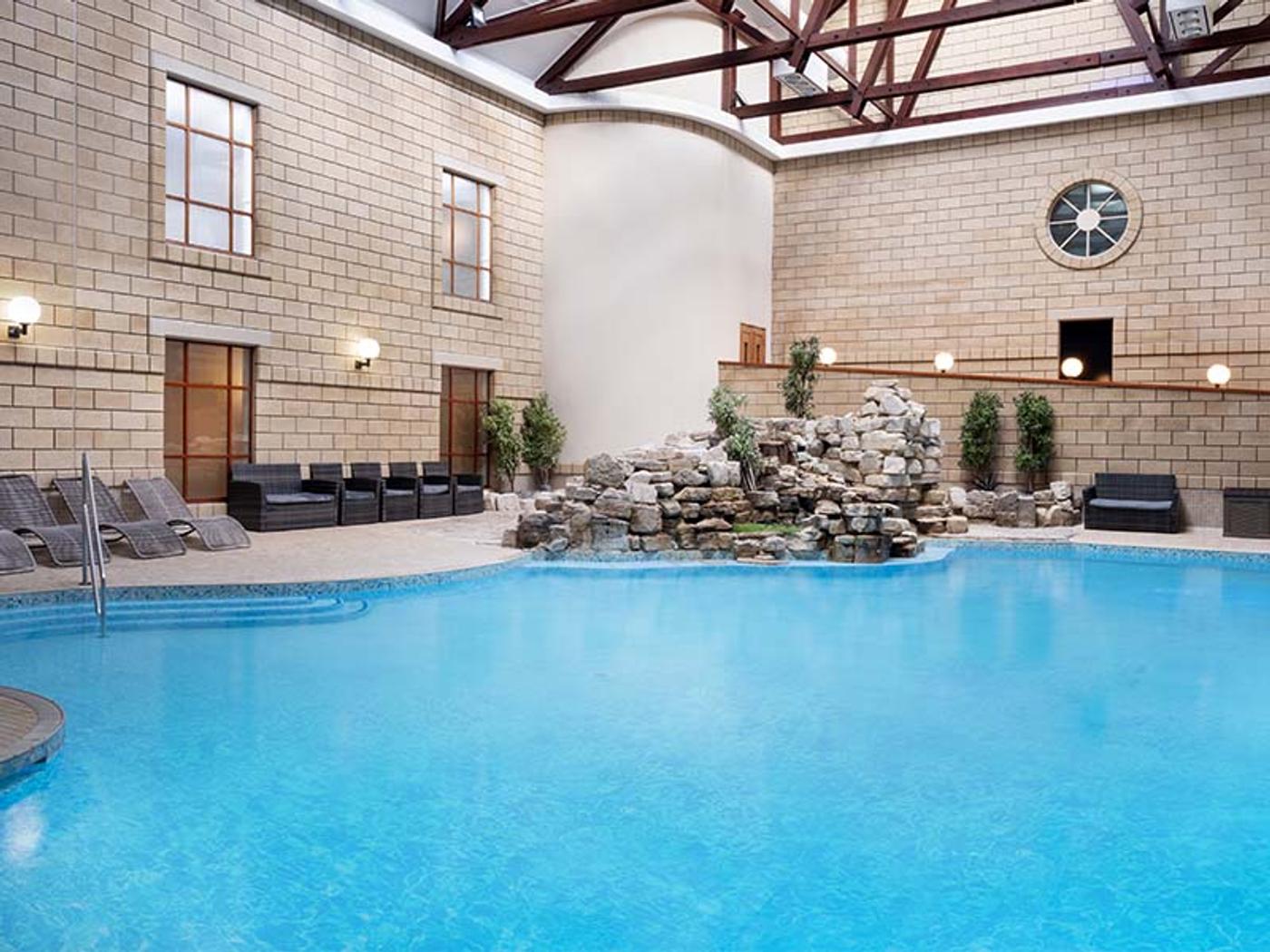 Indoor swimming pool with a rock waterfall feature at Delta Hotels by Marriott Tudor Park Country Club's spa