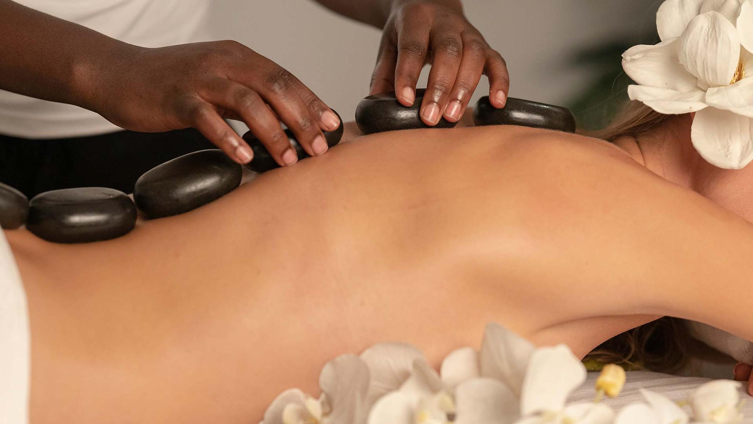 Therapist applying hot stones to a guest's back during a spa treatment