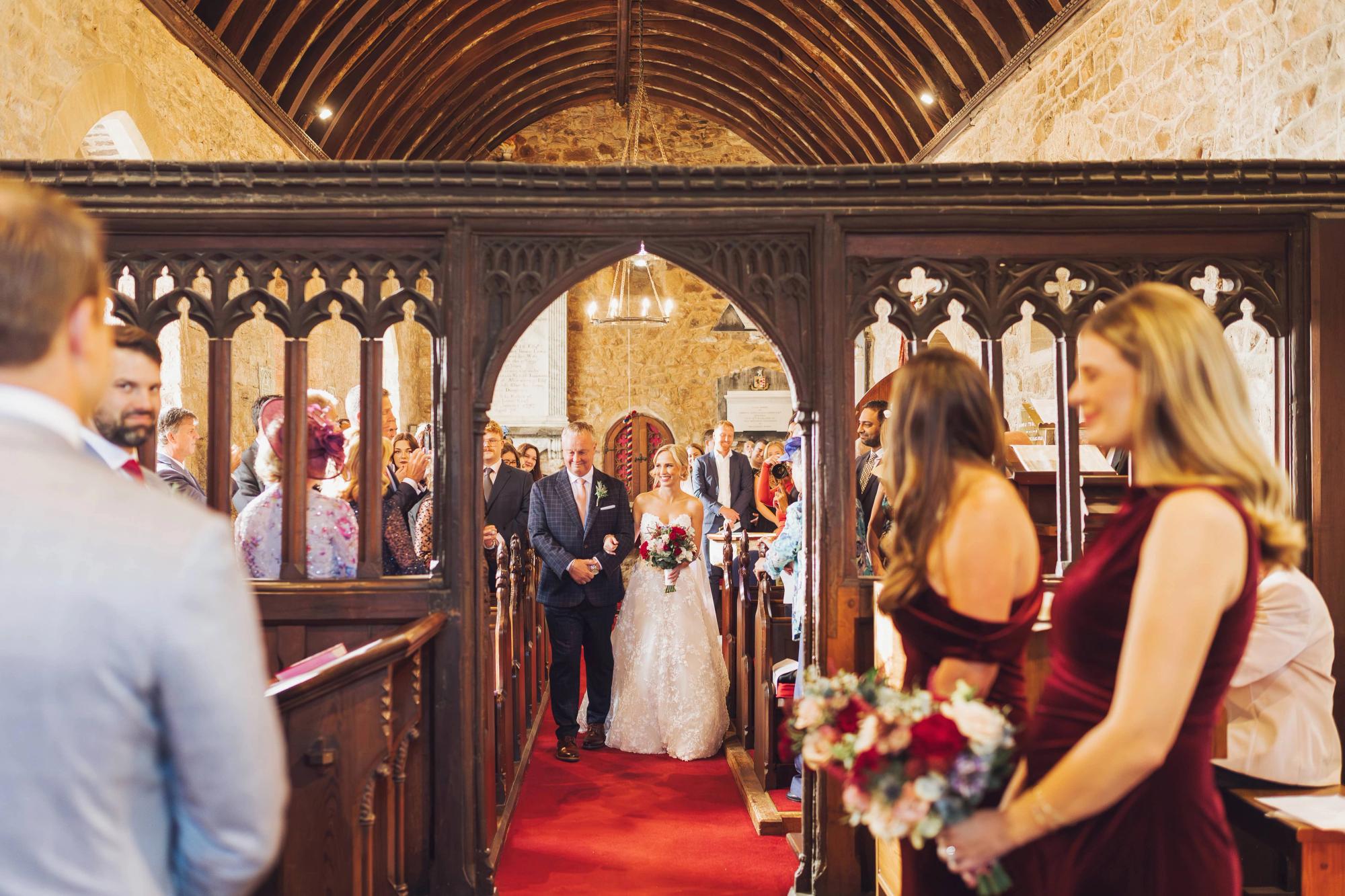 Bride walking down the aisle of a historic chapel with her father