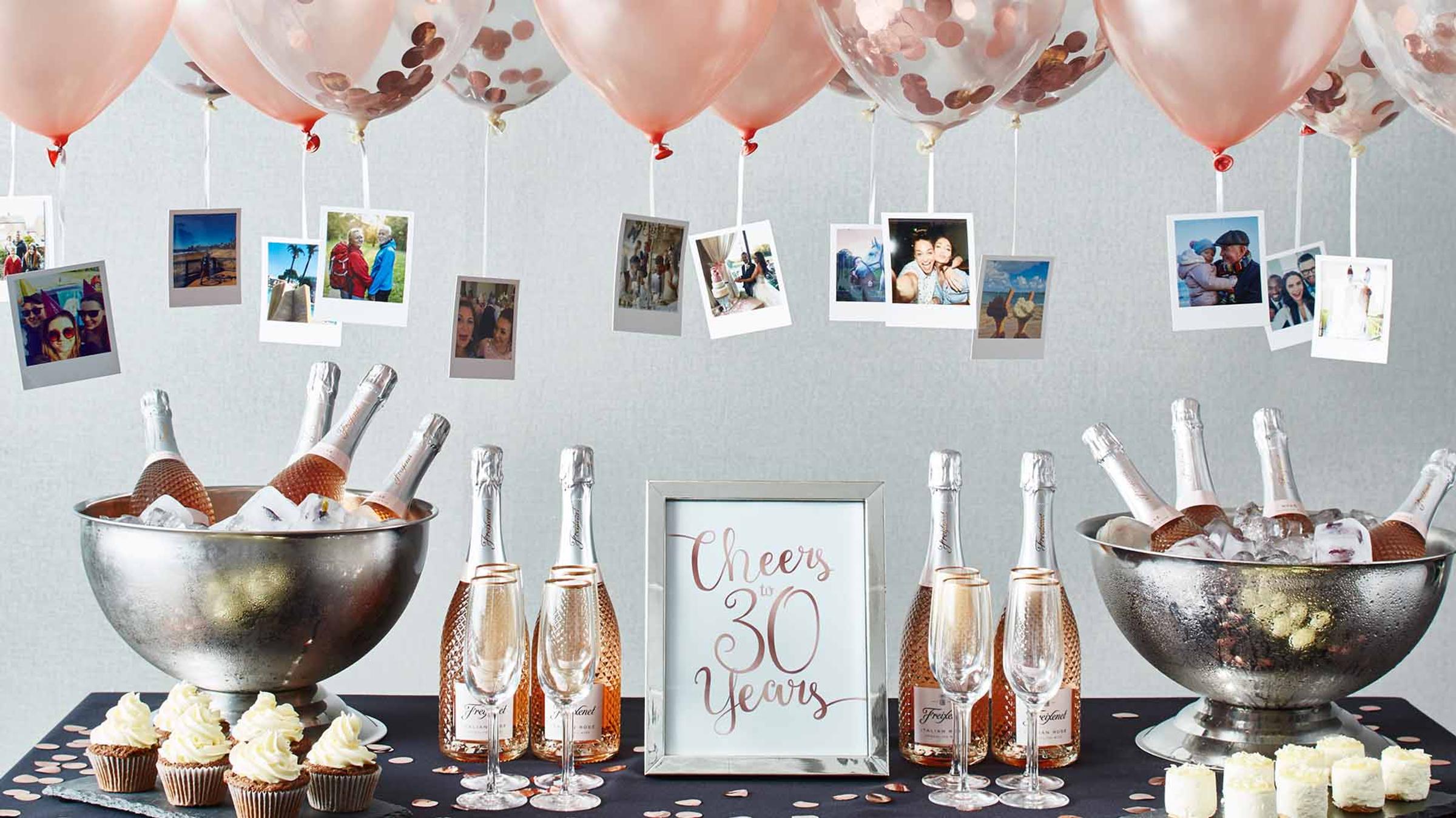 Polaroid photos hanging from balloons above a celebration dessert table at Delta Hotels Breadsall Priory Country Club