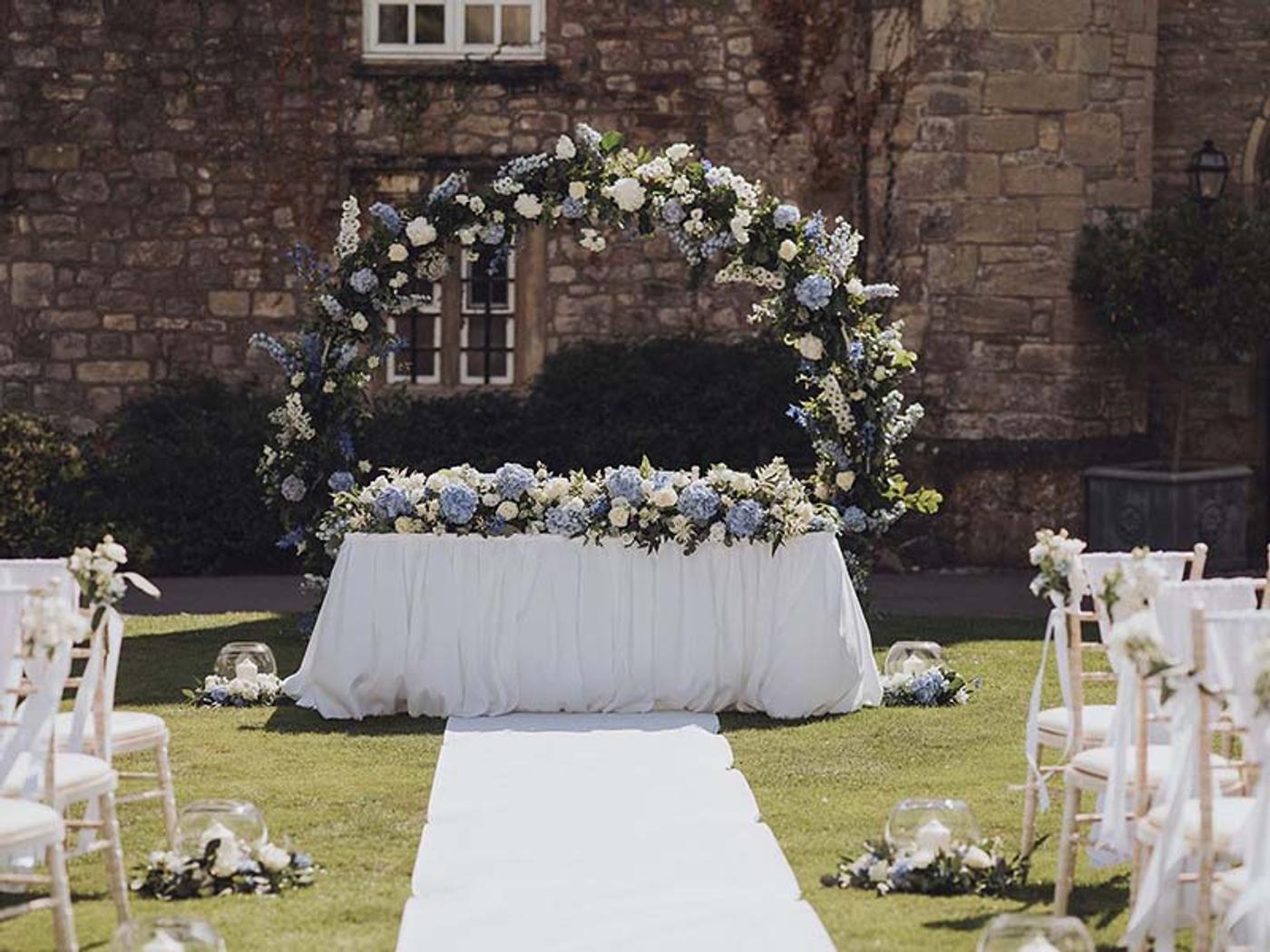 Outdoor wedding ceremony with a floral arch against Delta Hotels St. Pierre Country Club's stone walls