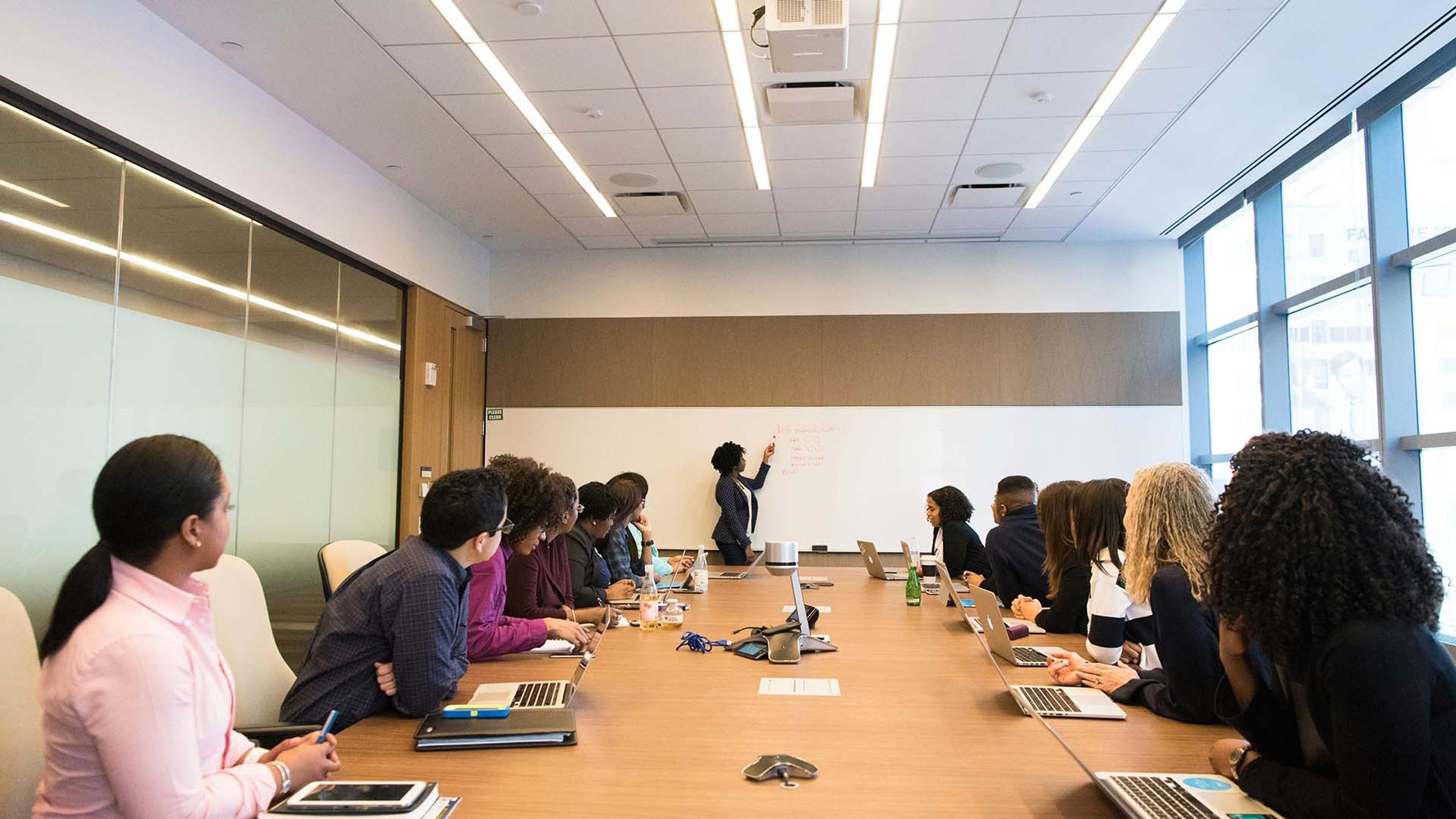 Boardroom meeting with a presenter writing on a whiteboard