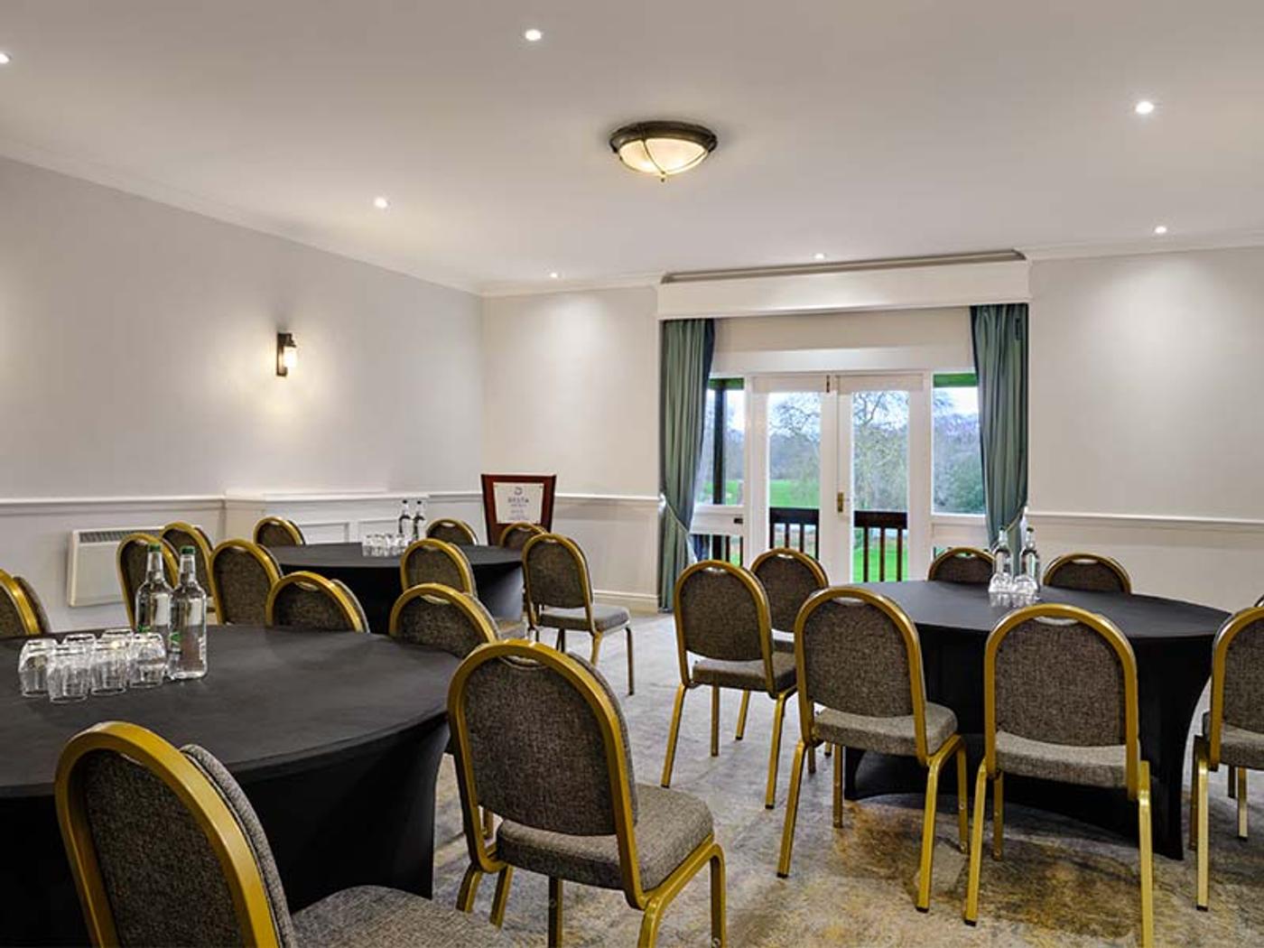 Meeting room set cabaret-style with round tables and doors onto the garden