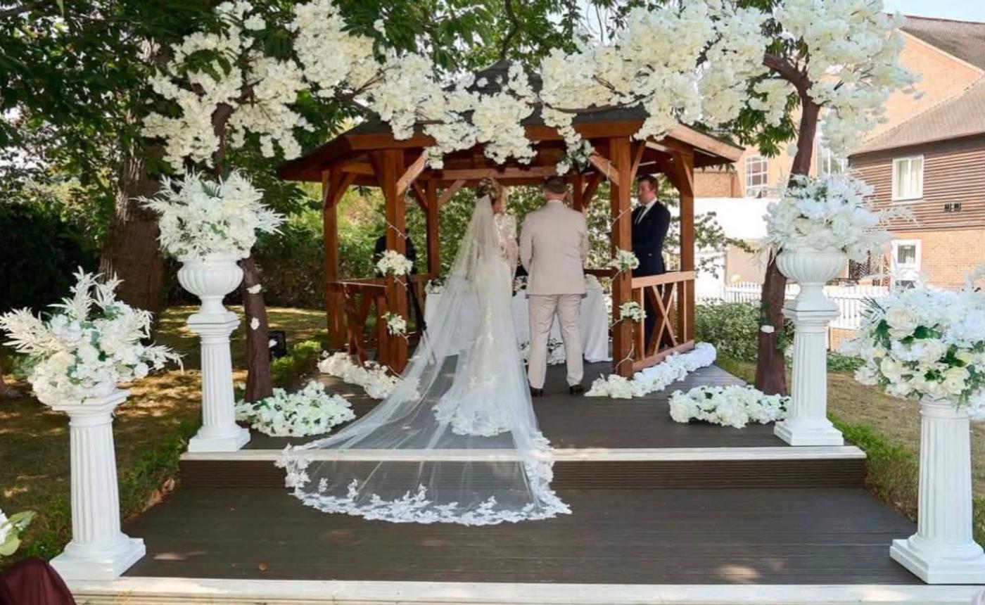 Bride and groom standing under wedding arch.