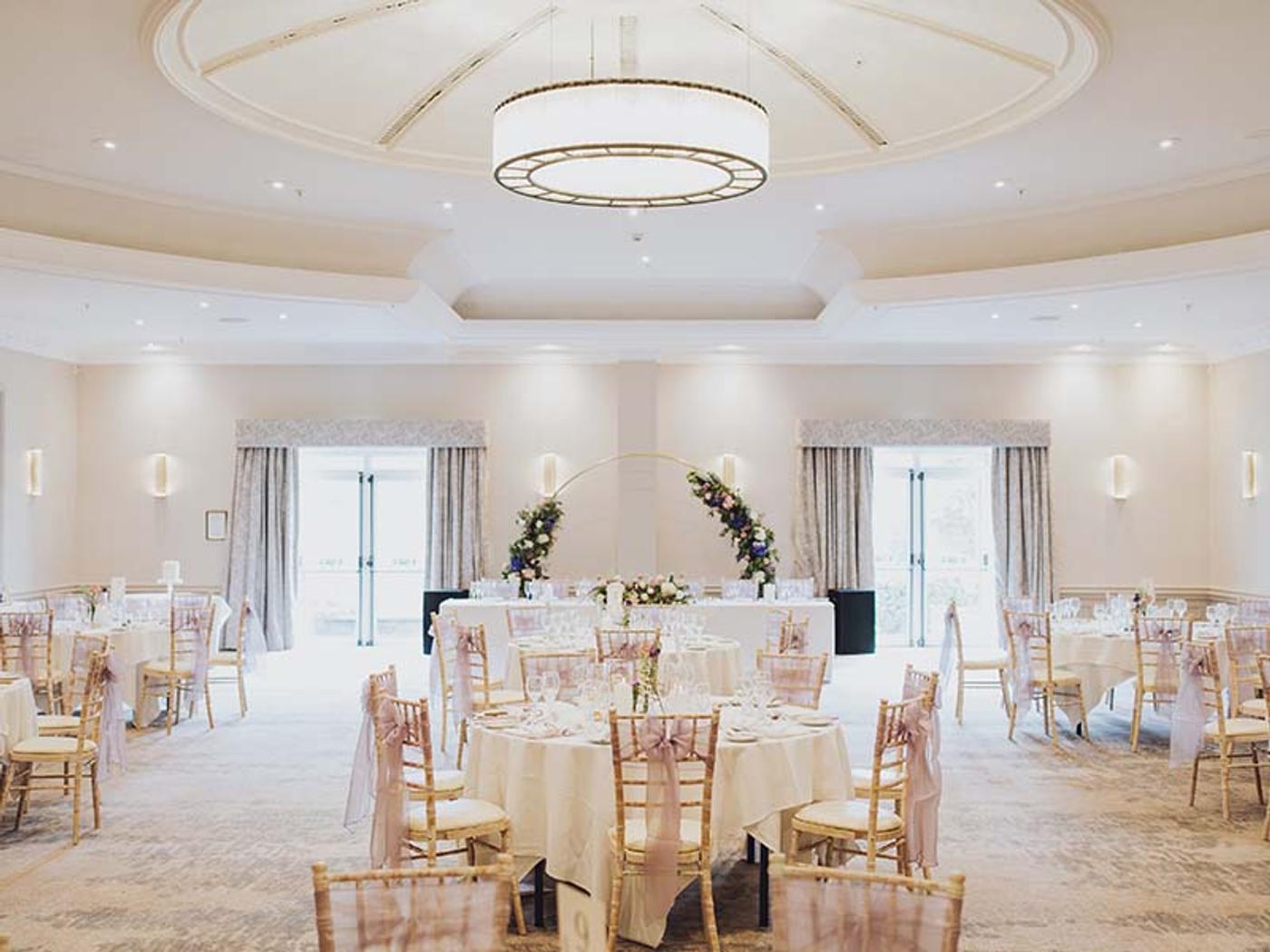 St. Pierre Suite set up for a wedding reception with round tables and a floral arch