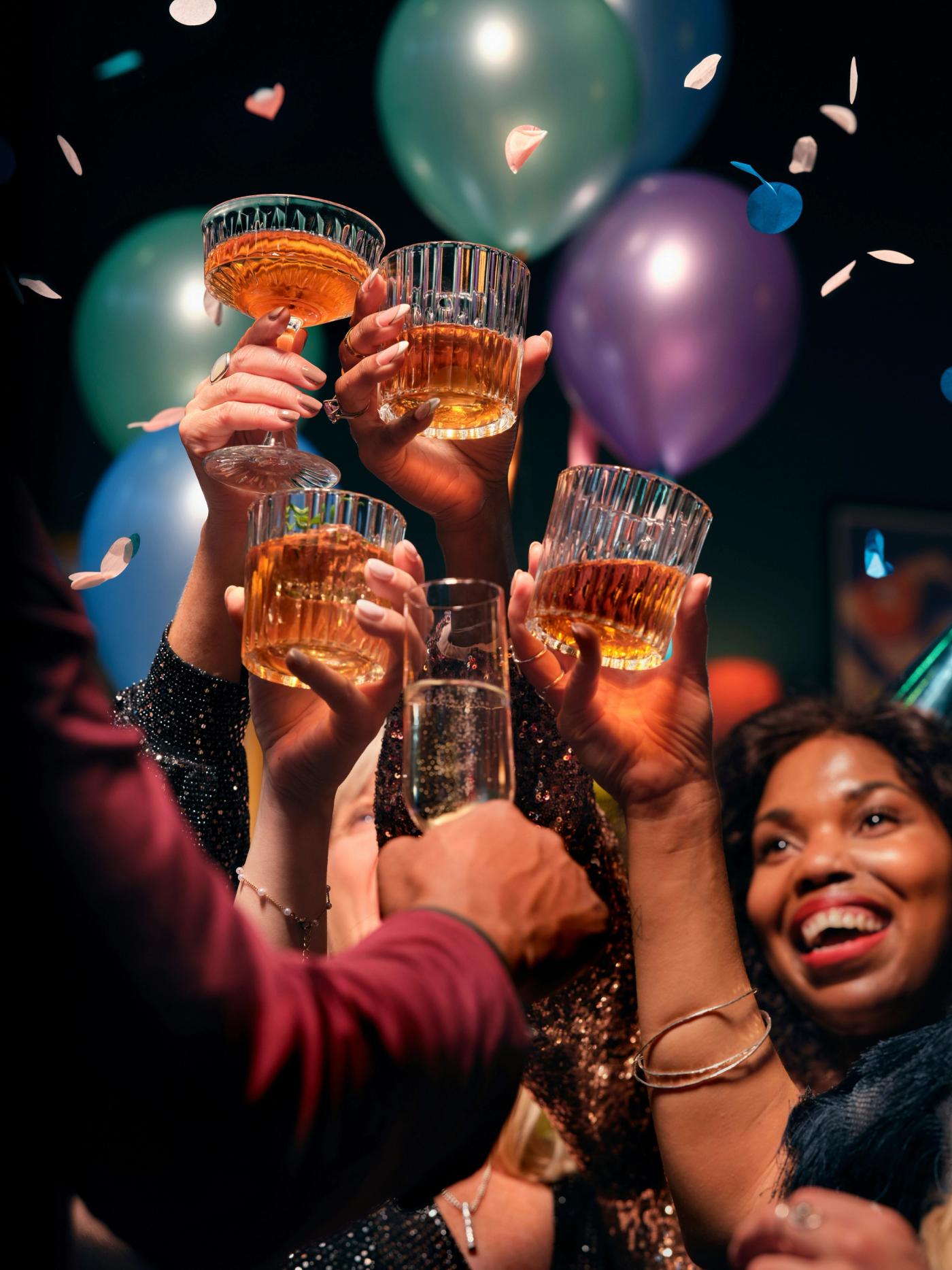 People saying cheers in front of balloons and confetti