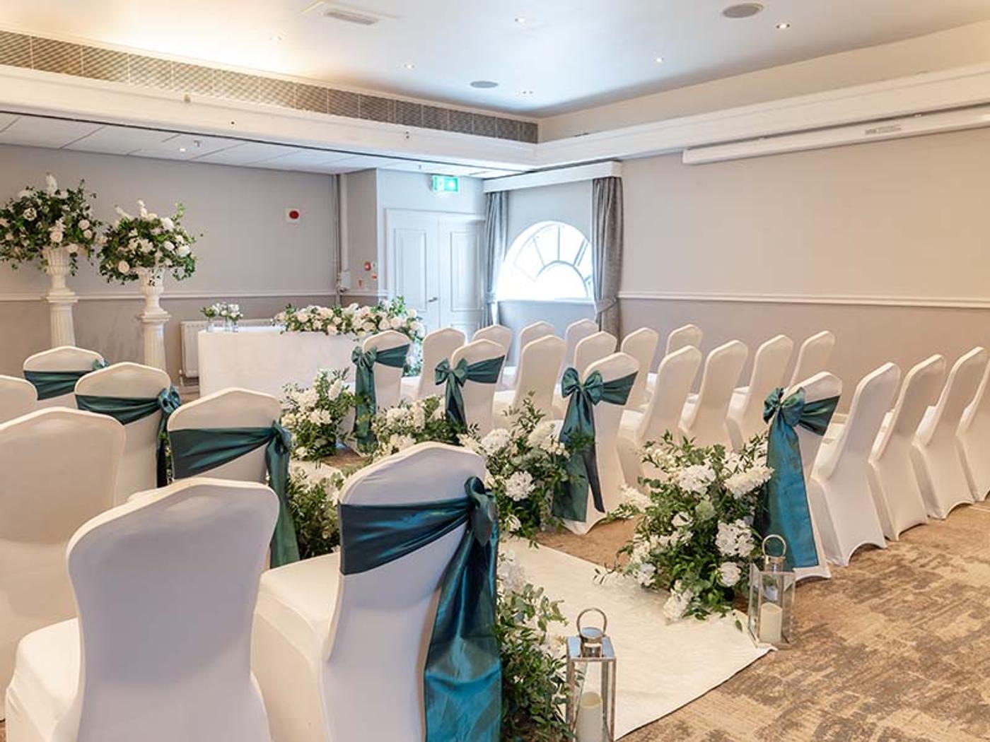 Ceremony room set up with white chair covers and teal sashes at Delta Hotels by Marriott Tudor Park Country Club