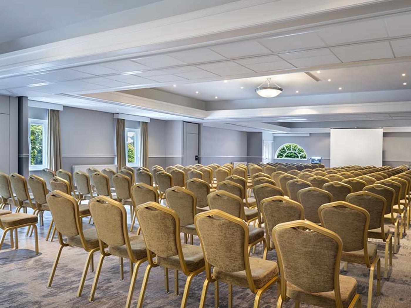 Thurnham Suite set cabaret-style with round tables and a projector screen