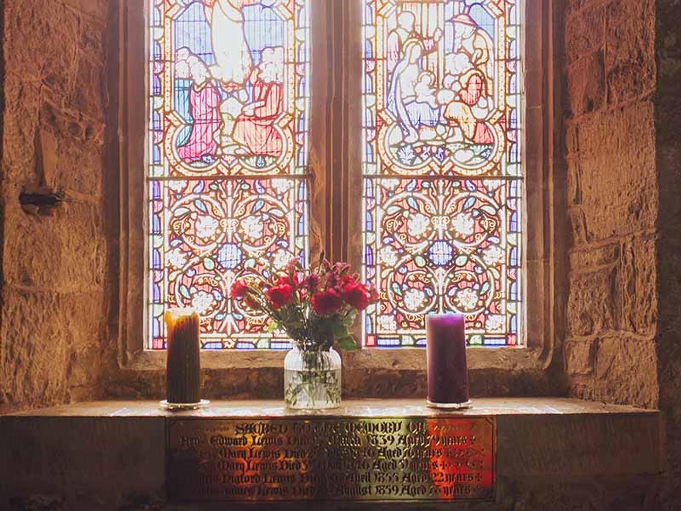 Stained glass window inside St. Peters Church with flowers and candles
