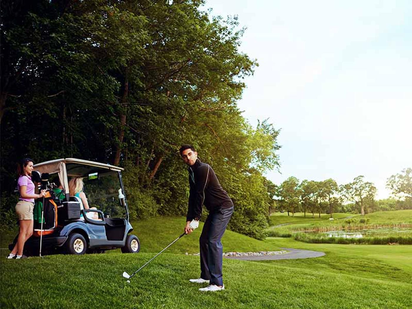 Close-up of a golf club and ball with autumn trees in the background