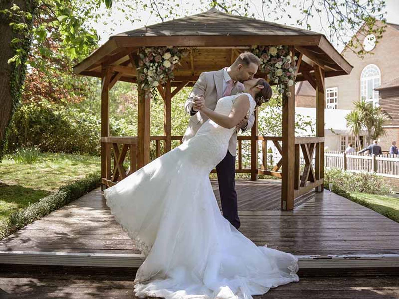 Bride and groom kissing in front of the wooden gazebo at Delta Hotels by Marriott Tudor Park Country Club