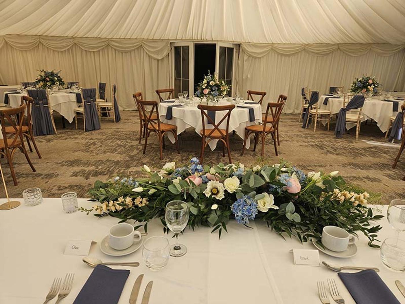 Place setting with name cards and a floral table runner in the Marquee