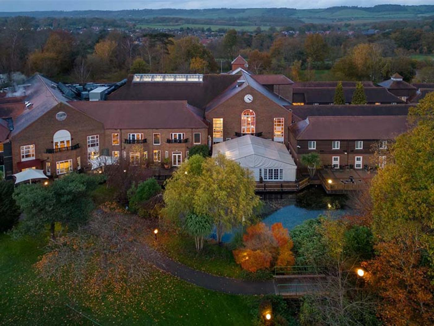 Aerial view of Delta Hotels by Marriott Tudor Park Country Club's clubhouse, marquee and lake at dusk