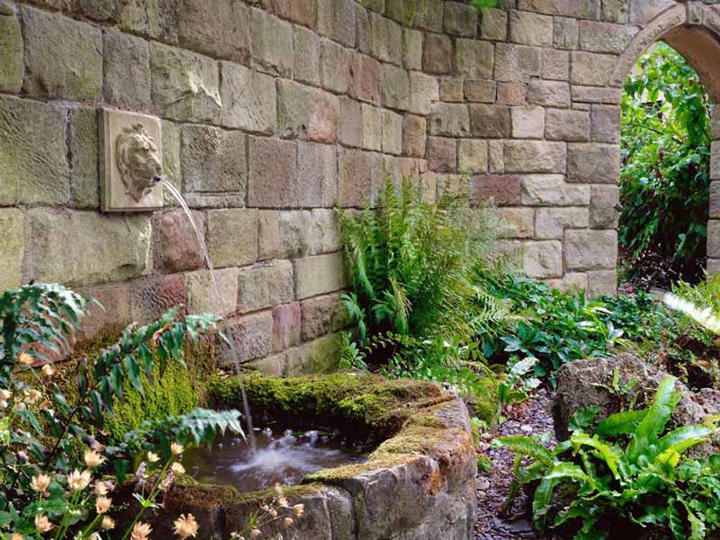 Ornamental stone lion-head fountain in Delta Hotels Breadsall Priory Country Club's gardens