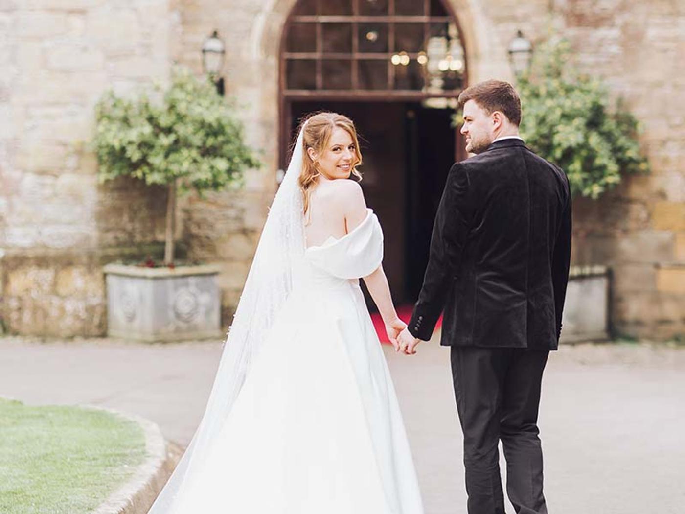 Bride glancing back at the archway entrance with her groom