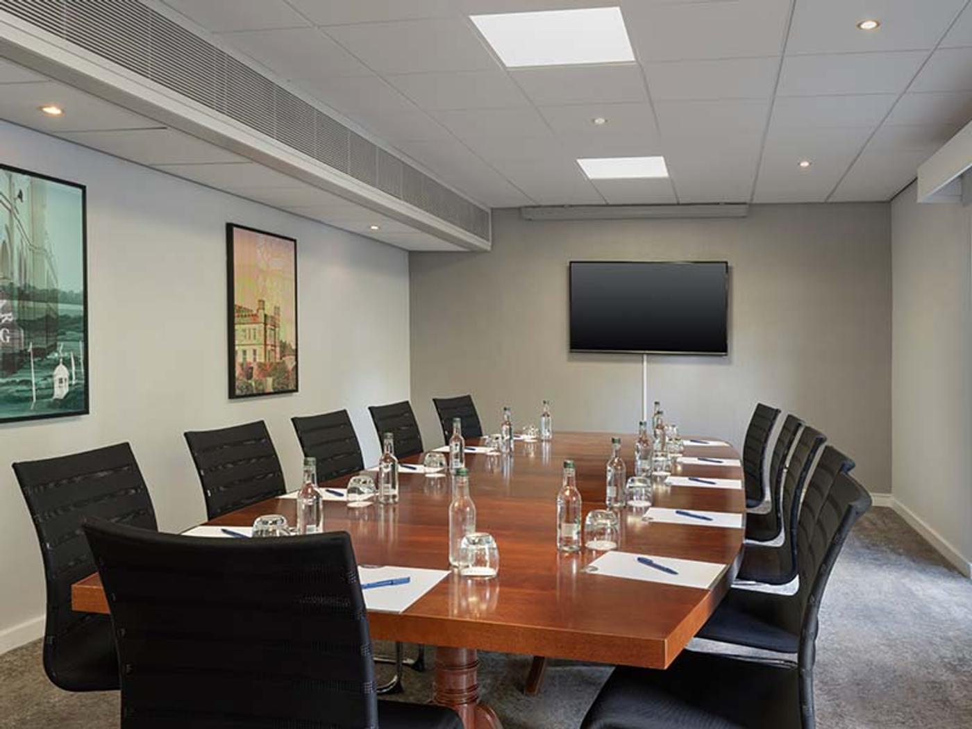 Langley boardroom set with a long table, leather chairs and a wall-mounted screen