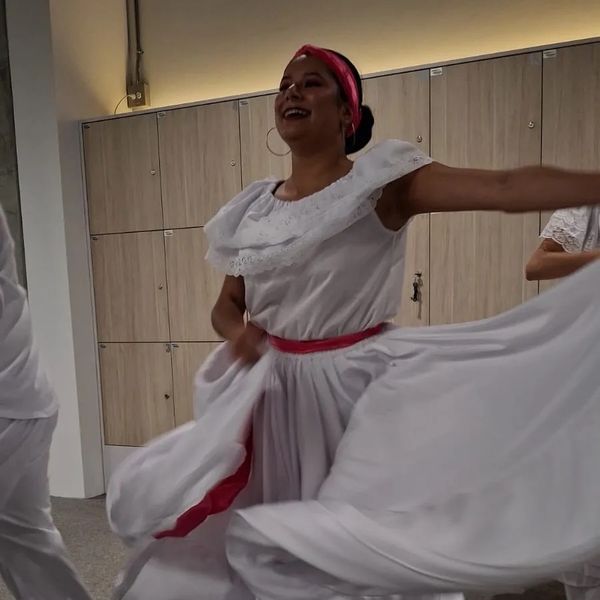 Bailarina con pollera blanca y cinta roja sonriendo