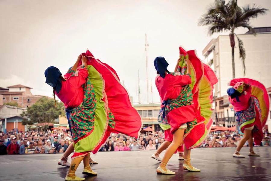 Bailarinas con faldas rojas y amarillas girando frente al público
