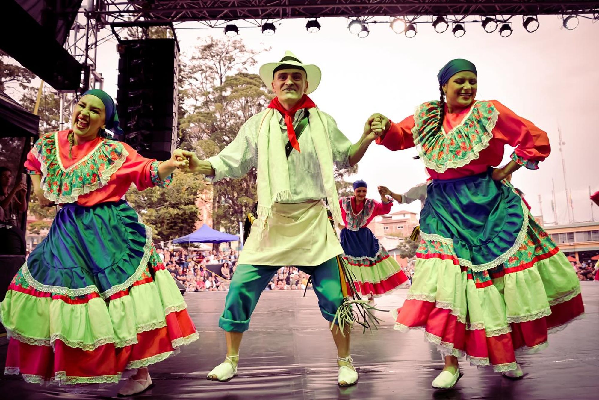 Pareja con traje campesino de colores bailando en tarima al aire libre