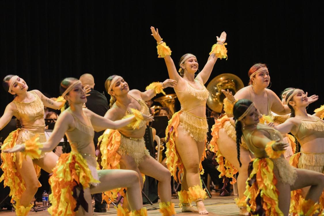 Bailarinas con vestuario de fuego frente a la banda sinfónica