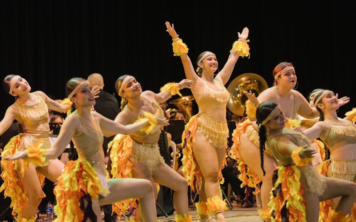 Bailarinas con vestuario de fuego frente a la banda sinfónica