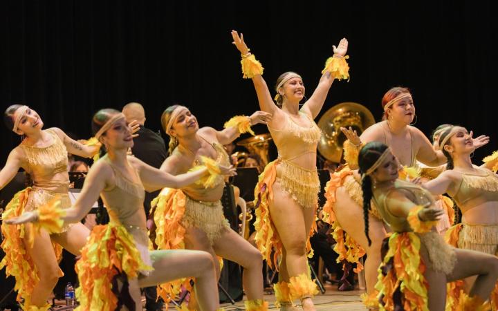 Bailarinas con vestuario de fuego frente a la banda sinfónica