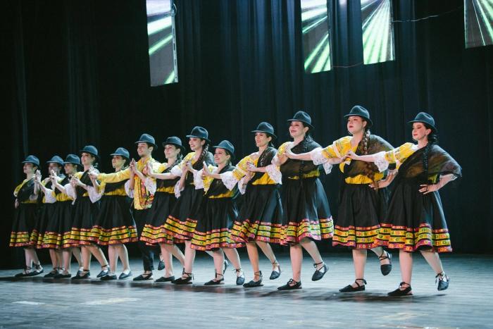 Fila de bailarinas con falda negra y sombrero