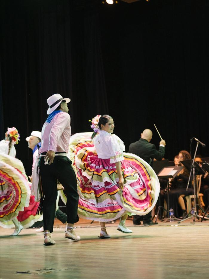 Pareja bailando con pollera de colores frente a la banda