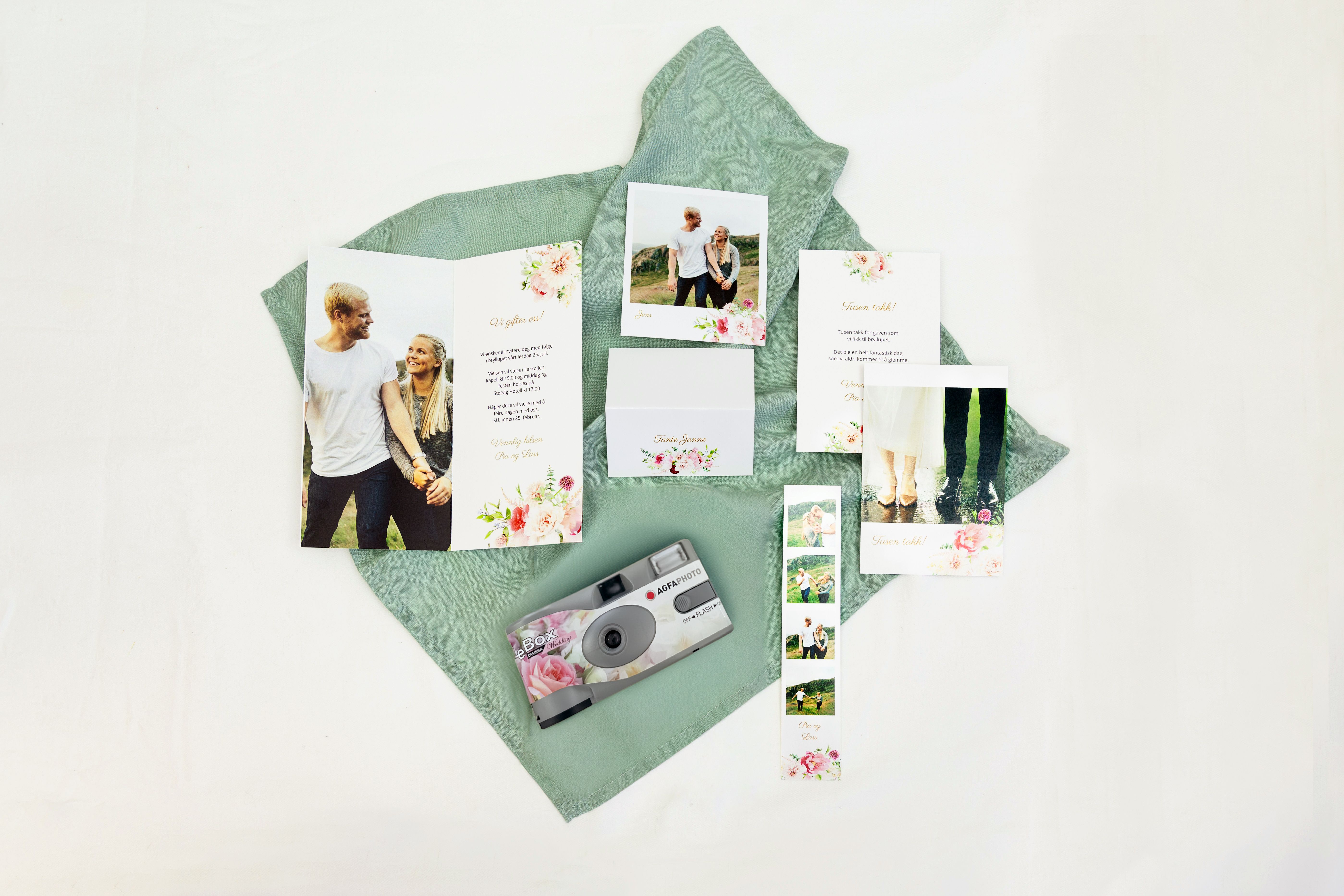 Ulike trykksaker og engangskamera til bryllup som ligger oppå en grønn duk