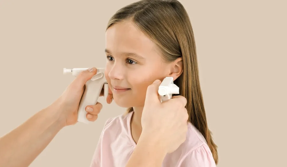 Liten jente som får hull i ørene med medisinsk hulltagning