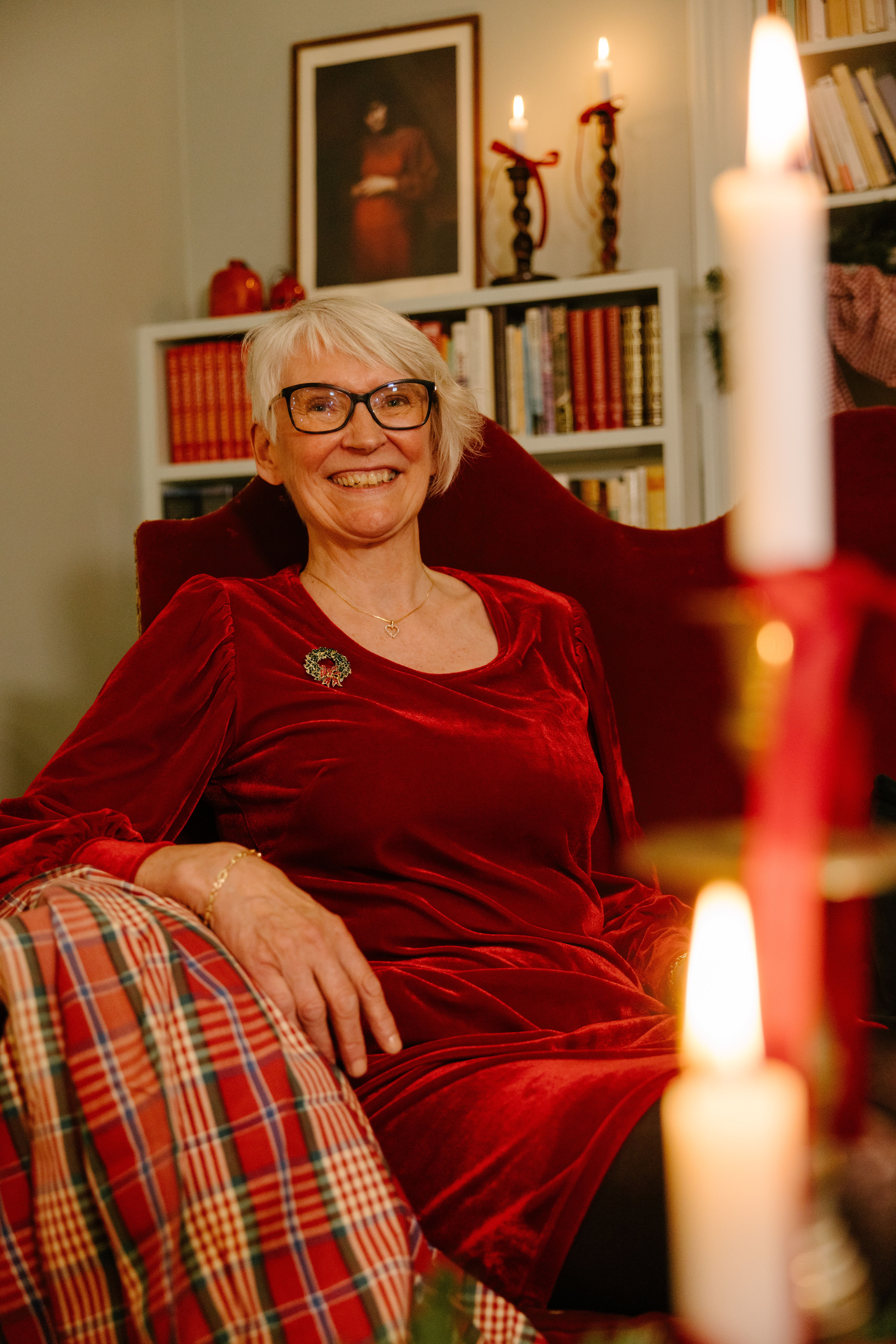 Kvinne som smiler i rød julekjole og sitter på en sofa