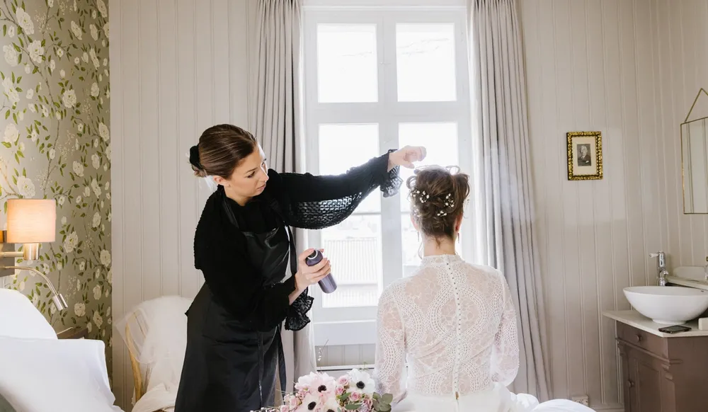brud får hjelp til håret på bryllupsdagen