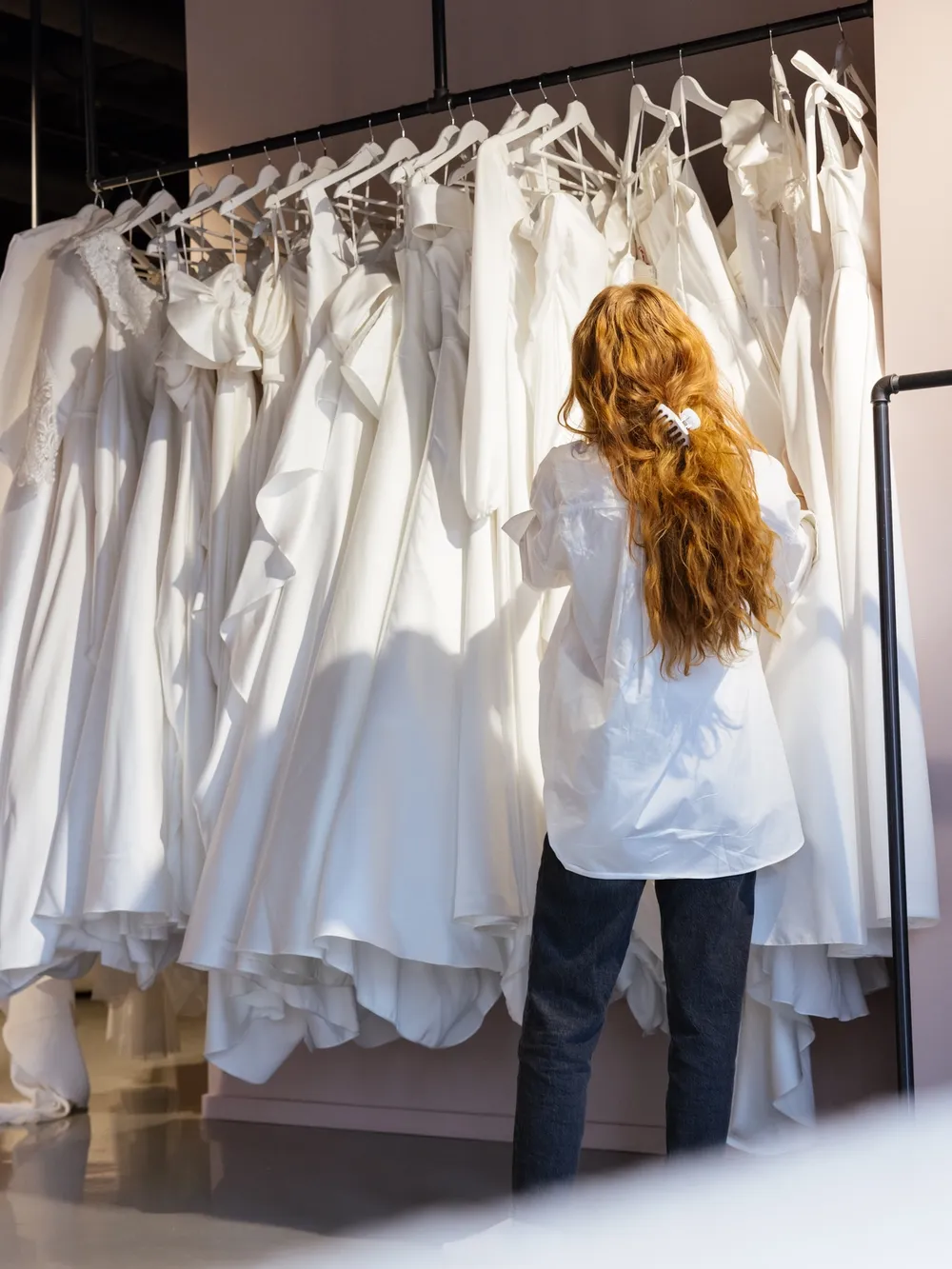 Stylist velger ut brudekjoler i salong