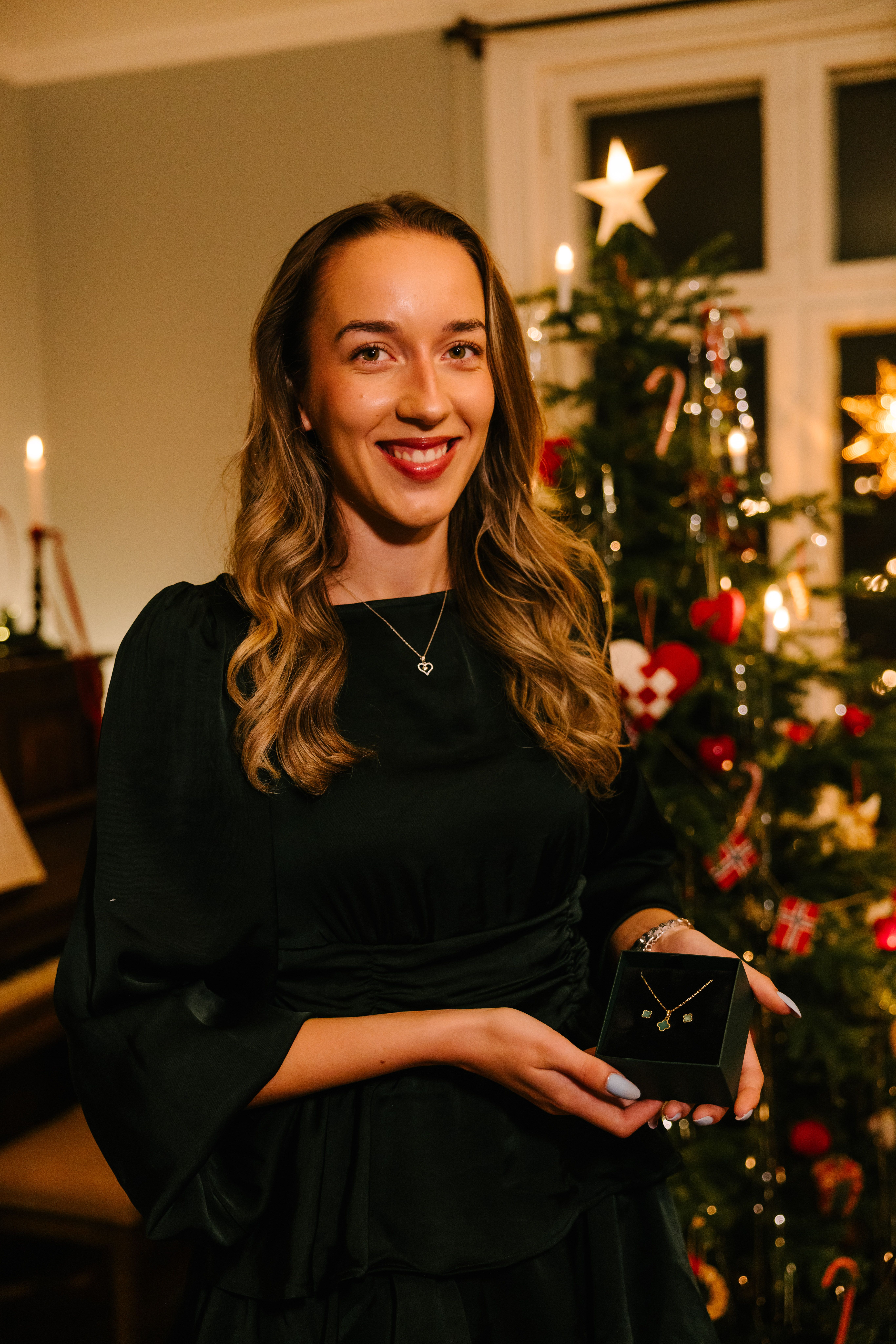 Kvinne som smiler og holder et smykkesett i en sort gaveeske
