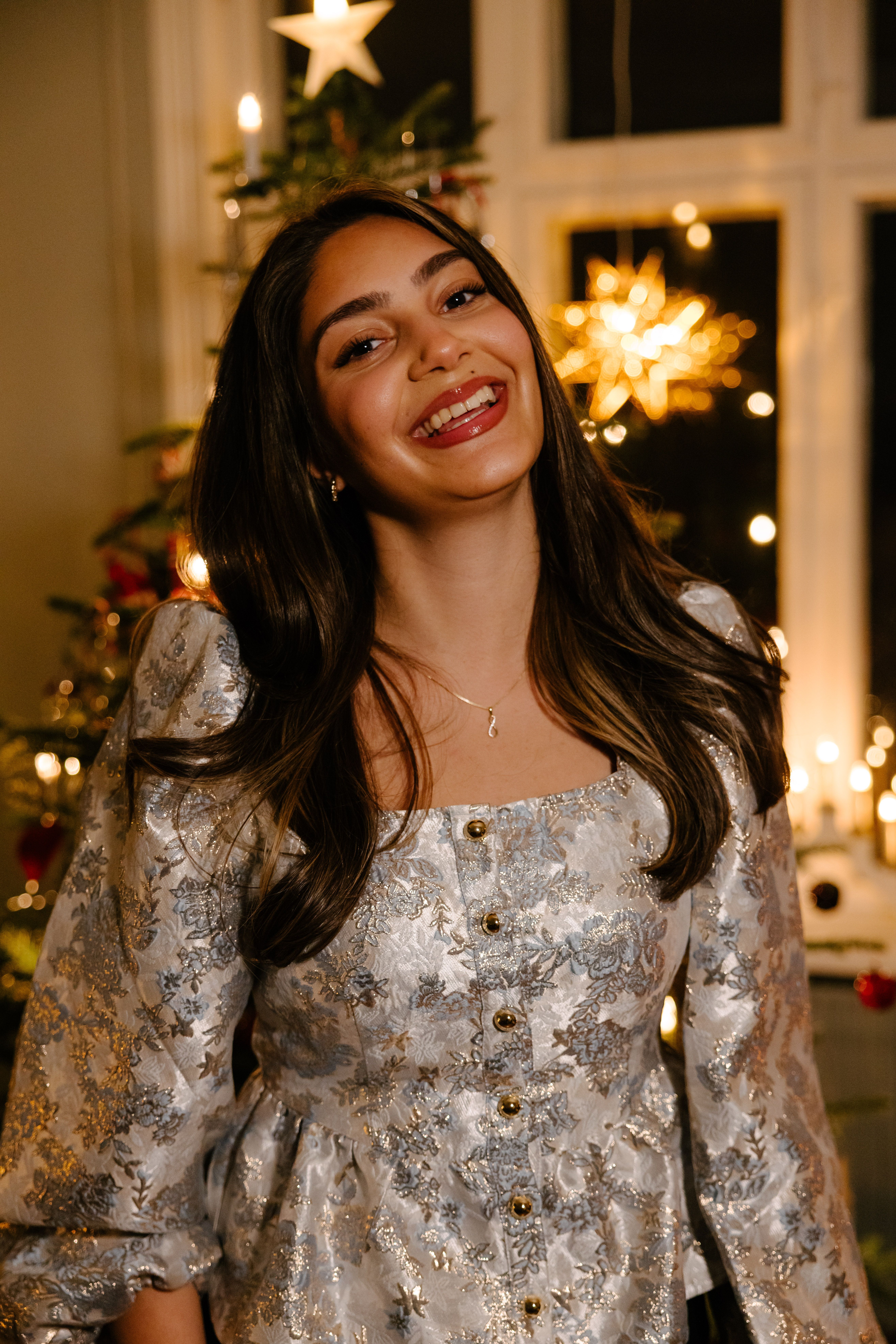 Kvinne som smiler med juletre i bakgrunn
