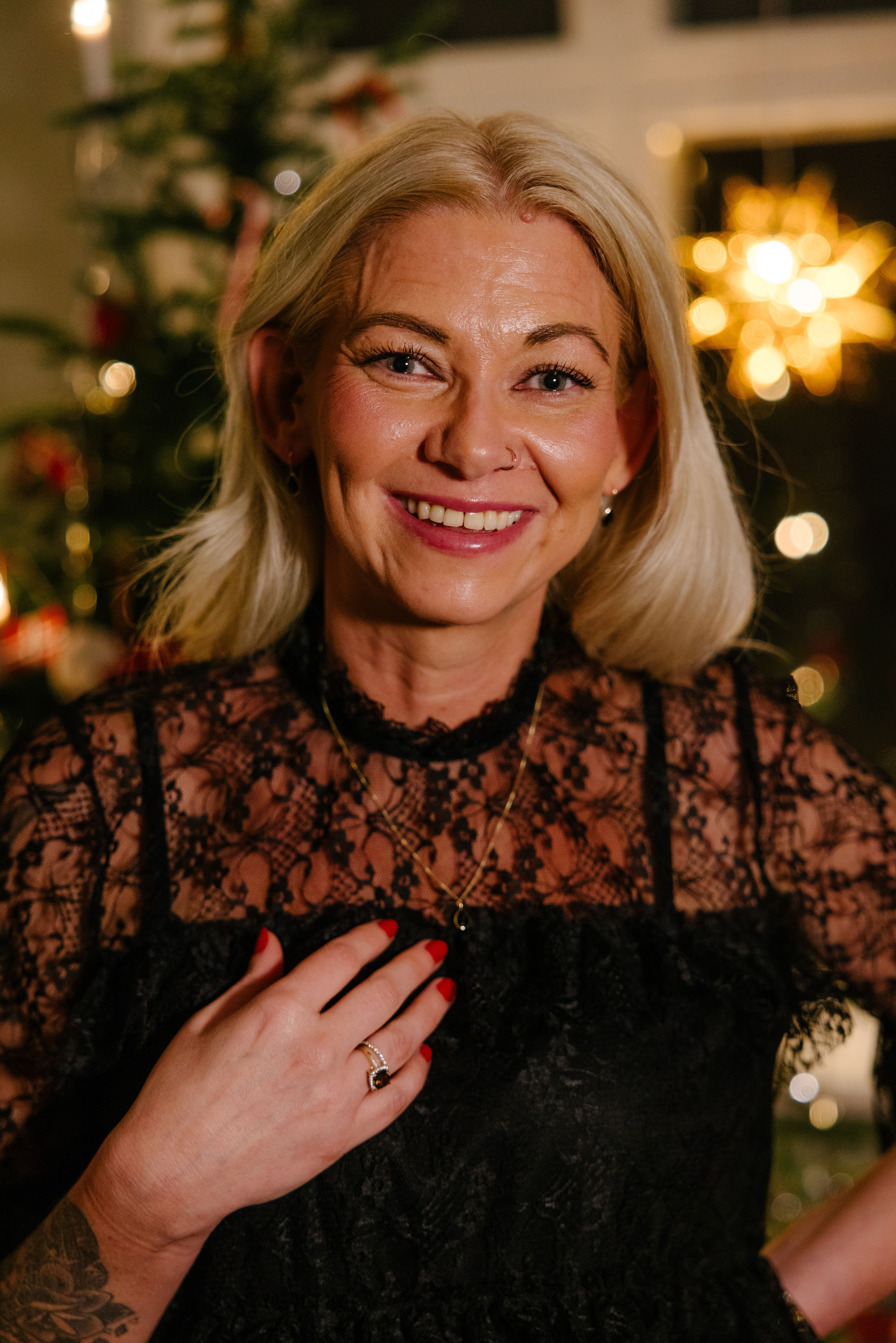 Kvinne som smiler med smykker foran et juletre