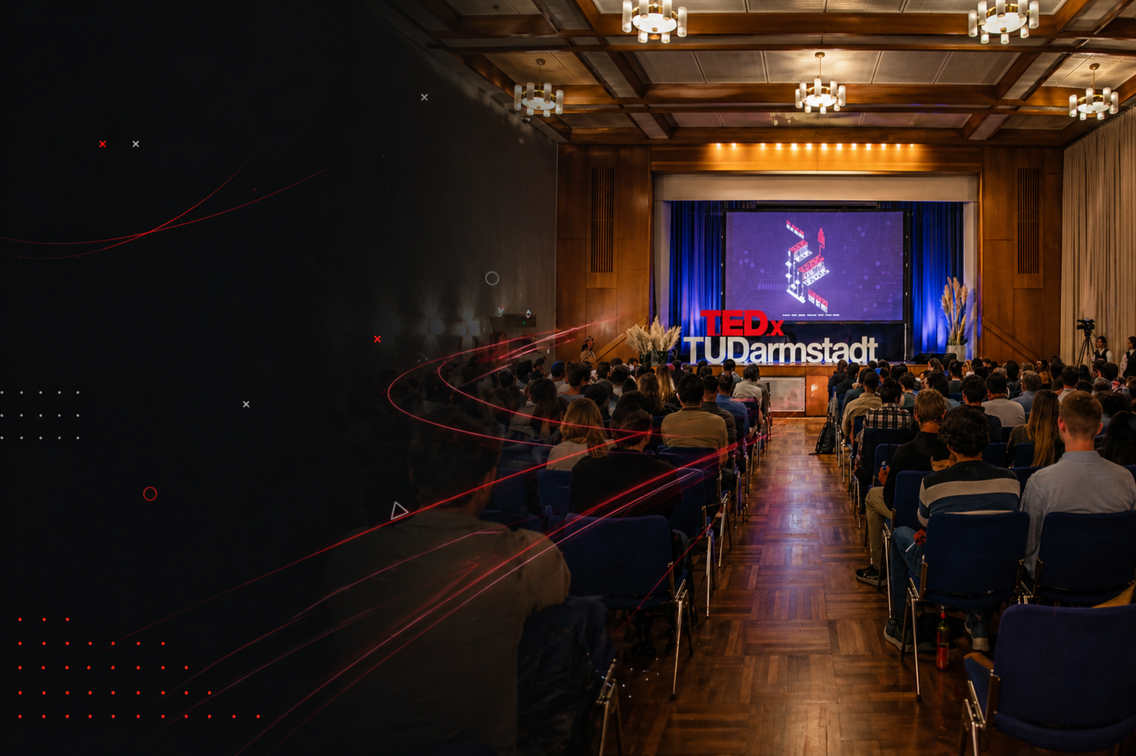 Audience attending a TEDxTUDarmstadt event with a speaker on stage in a red-lit auditorium