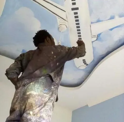 Man painting a mural with a plane