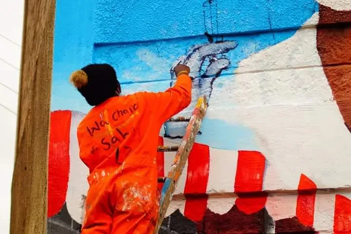 a man on a ladder painting a mural