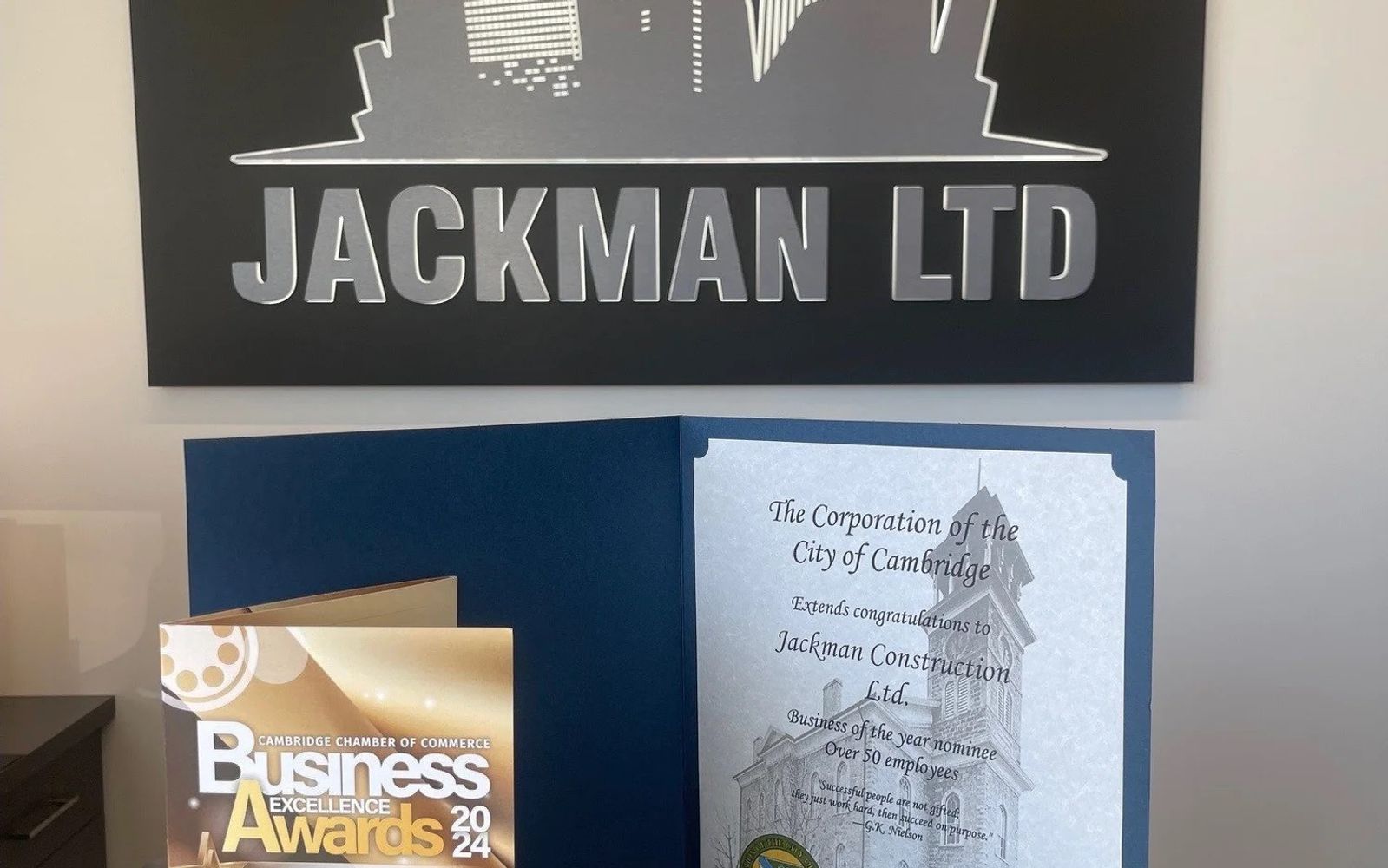 Cambridge Chamber of Commerce Business Excellence Awards 2024 program and City of Cambridge congratulations displayed with the Jackman Ltd wall sign.